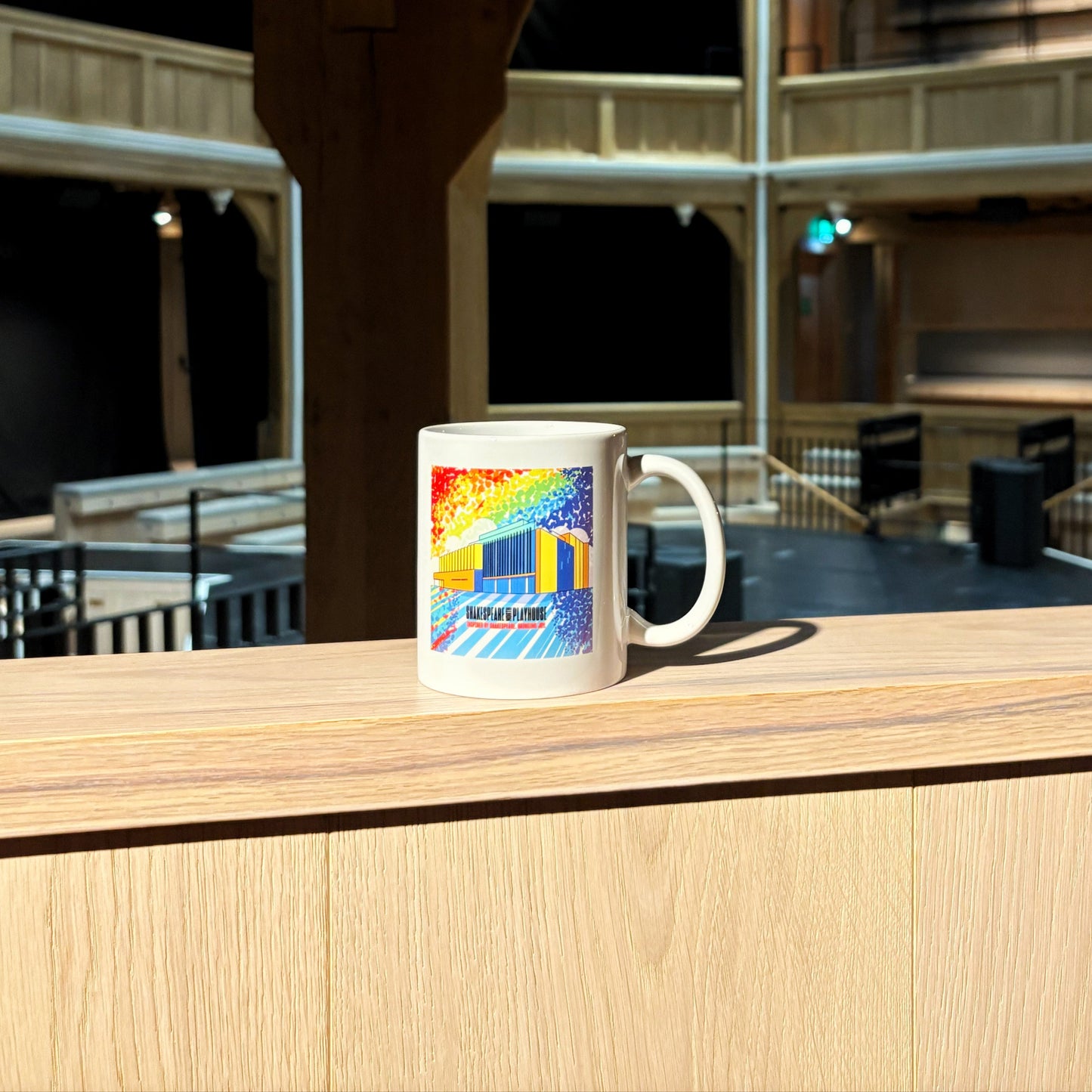 White mug featuring a rainbow illustration of the Shakespeare North building