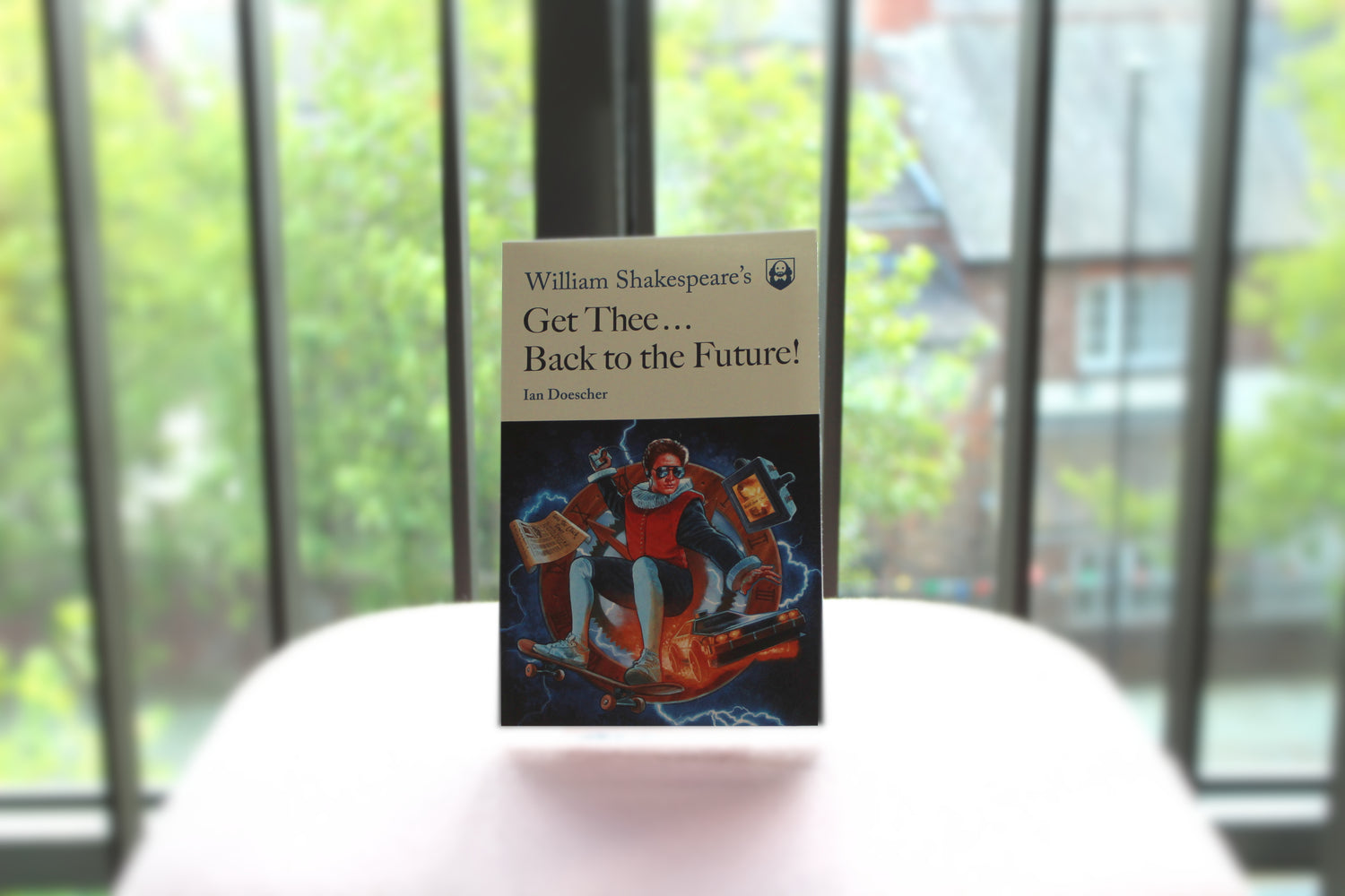 A book is on display - Get Thee Back to the Future with a window behind showing a backdrop of some greenery.
