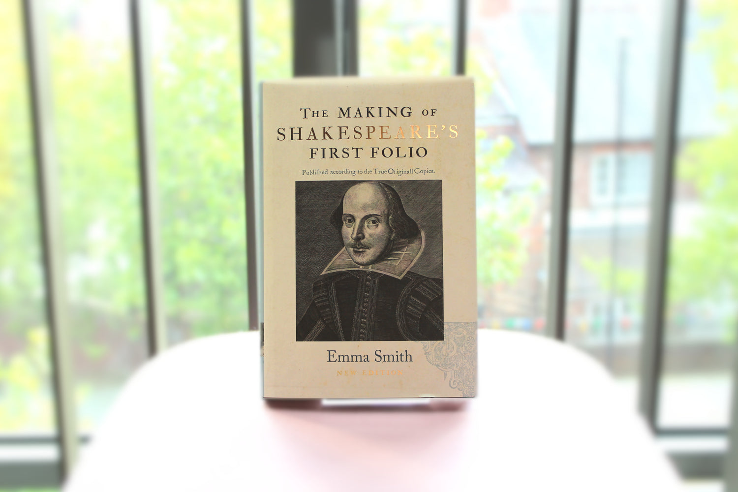 A book on display - The Making of Shakespeare's First Folio by Emma Smith. with a window behind showing a backdrop of some greenery.