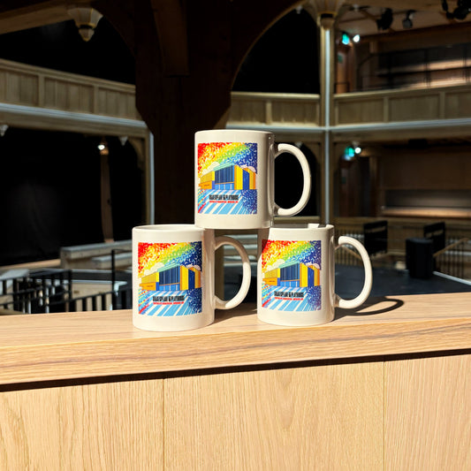 Three mugs stacked, each featuring a rainbow illustration of the front of the Shakespeare North building.