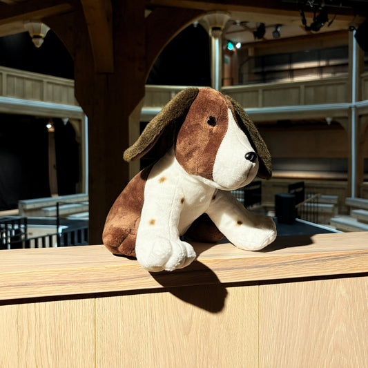 Plush dog toy on a wooden ledge.