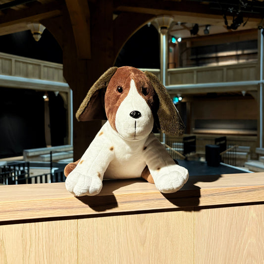 Plush dog toy on a wooden platform.